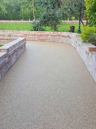 A resin bound driveway with brick walls on each side installed in Glasgow by Burgh Resin